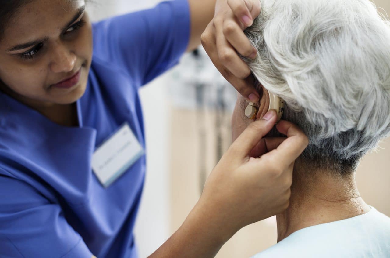 Woman getting her hearing aid adjusted by a professional.