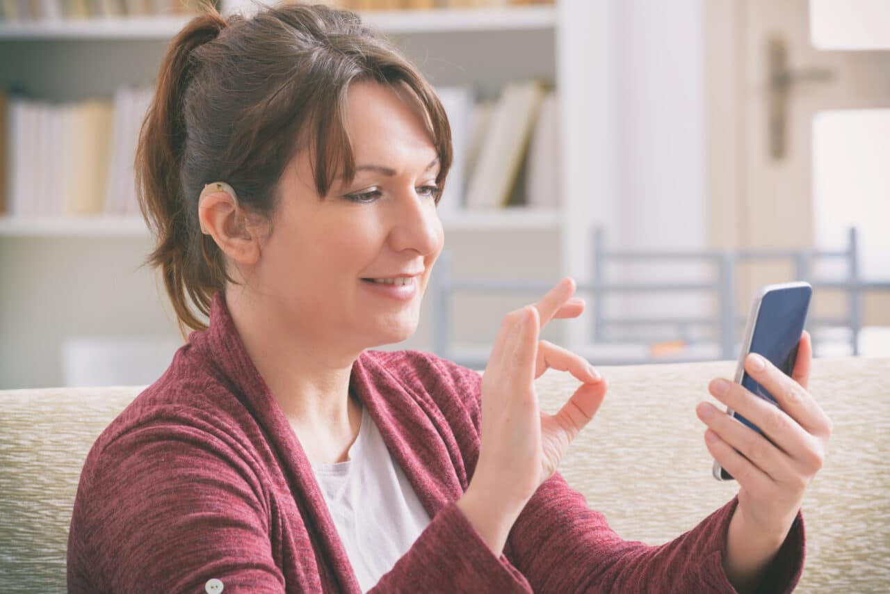 Woman with hearing aid using a smartphone.