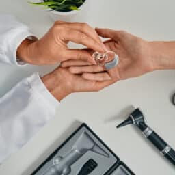 Audiologist placing a hearing aid in their patient's hand
