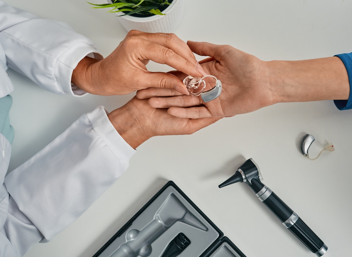 Audiologist placing a hearing aid in their patient's hand