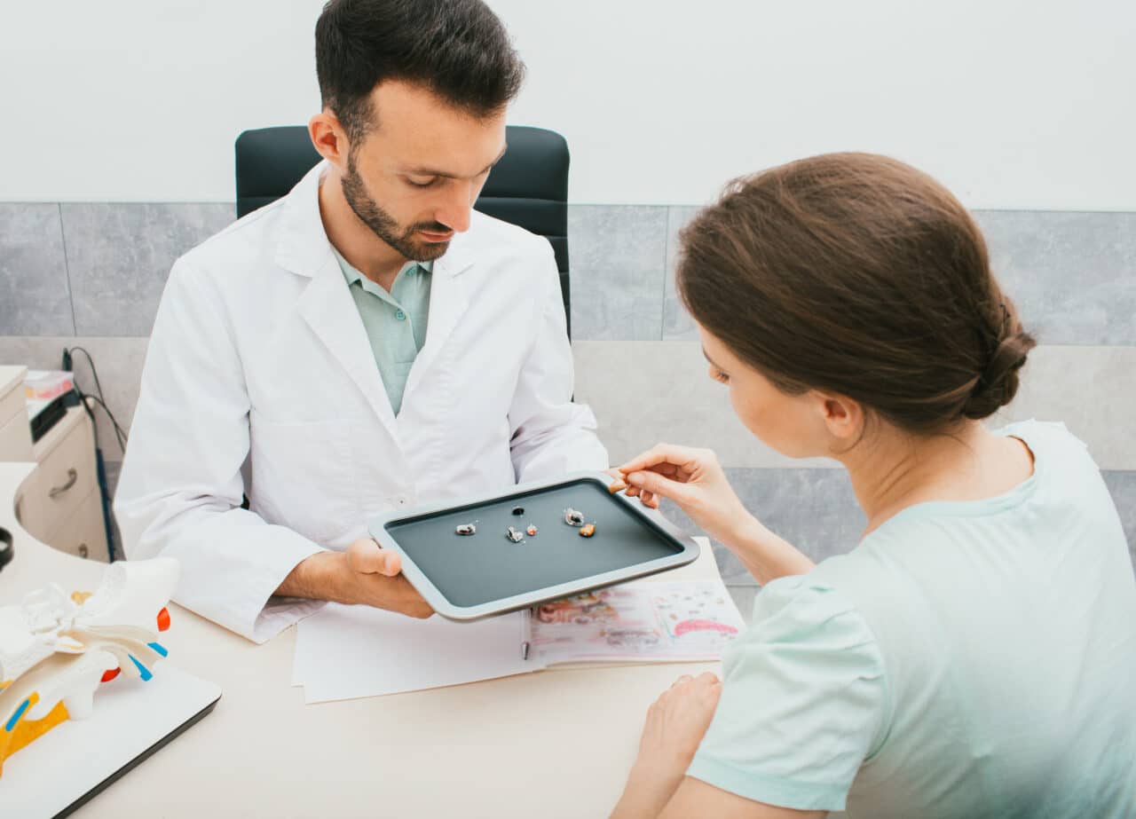 Audiologist helping a female patient choose a pair of hearing aids.