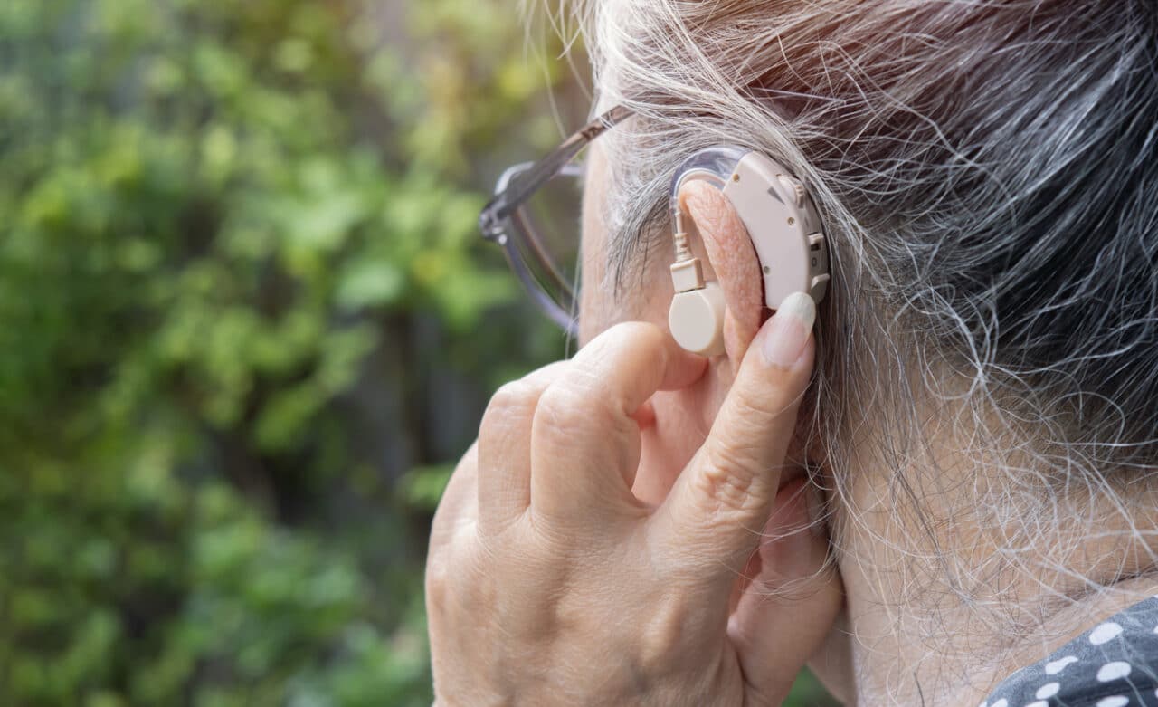 Woman adjusts hearing aid